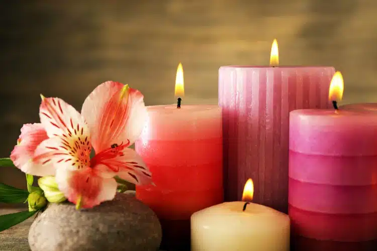 Bougies roses allumées avec un lys et une pierre de spa pour une ambiance zen et relaxante.